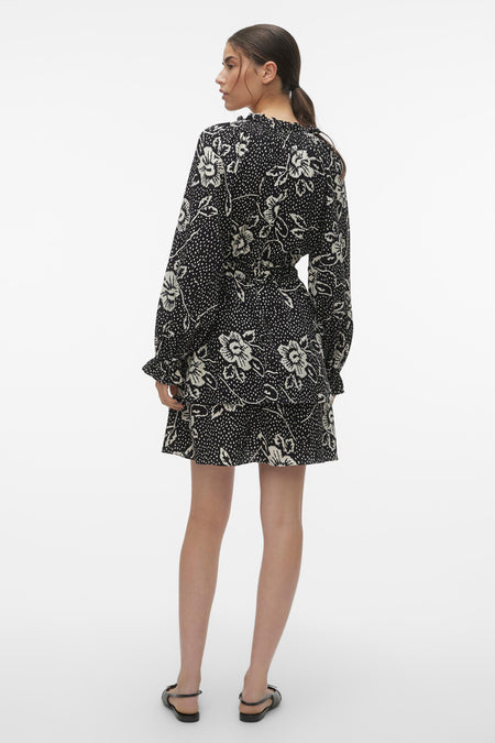 Jupe noire courte et courte manches longues de VERO MODA, avec une impression de fleurs et un détail plissé le la ligne du cou.