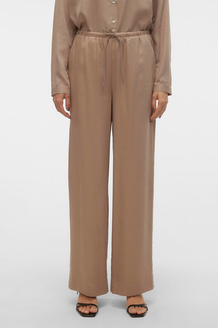 Zilveren broek van VERO MODA, met trekkoord en wijde pijpen, gedragen met sandalen.
