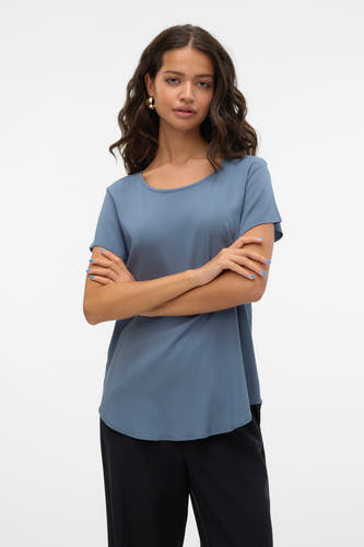 Blauwe blouse met korte mouwen van VERO MODA, met gekruiste armen, gecombineerd met zwarte broek.
