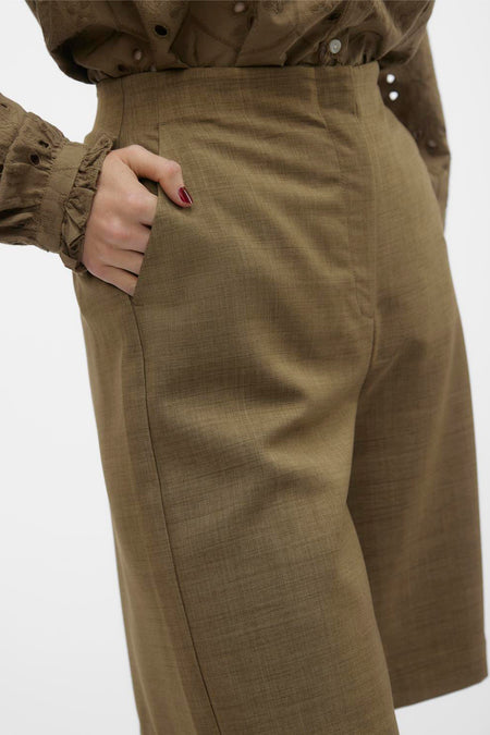 Bruine short van VERO MODA, met een hand in de zak en een bijpassende blouse.