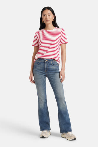 T-shirt rose à manches courtes de VERO MODA®, avec des rayures rouges, combiné avec un jean bleu et des baskets.