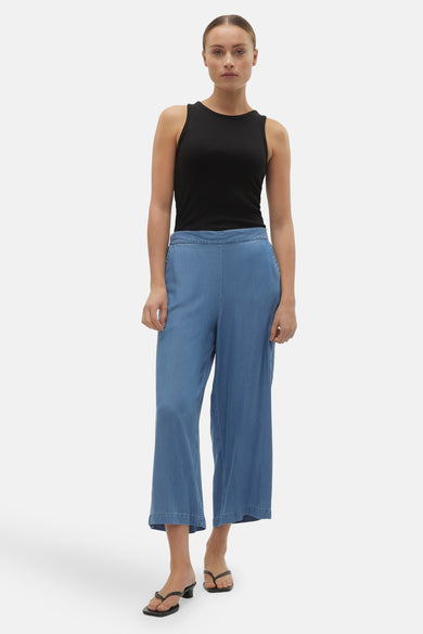Blauw denim broek van Vero Moda, gecombineerd met een zwarte top en sandalen met hak.