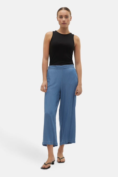 Blauwe denim broek van VERO MODA®, met wijde pijpen en een comfortabele pasvorm, gecombineerd met een zwarte tanktop.