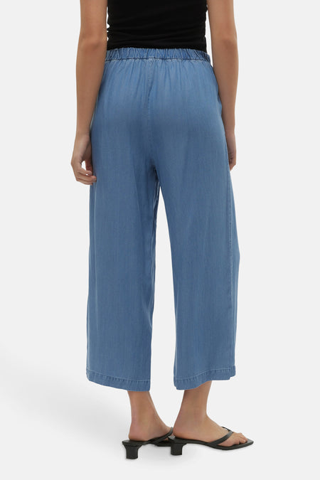 Blauwe broek van VERO MODA® met elastische tailleband, wijde pijpen en zwarte sandalen.
