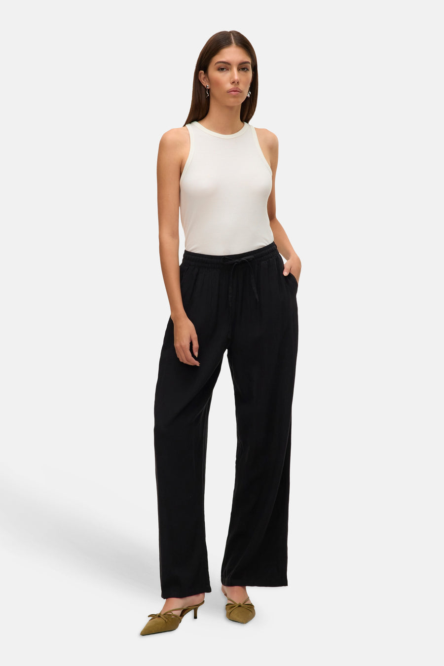 Zwarte broek van VERO MODA, met trekkoord, losse pasvorm en groene muiltjes.
