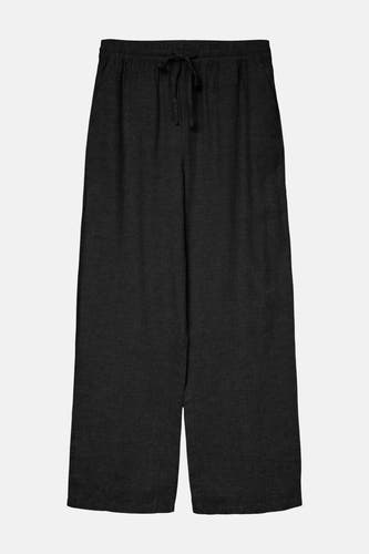 Zwarte broek van VERO MODA met trekkoord en wijde pijpen tegen een grijze achtergrond.