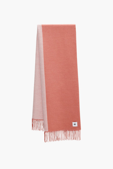 Écharpe d'hiver orange OPUS, avec des franges et stylée avec un pull rayé et un pantalon beige.