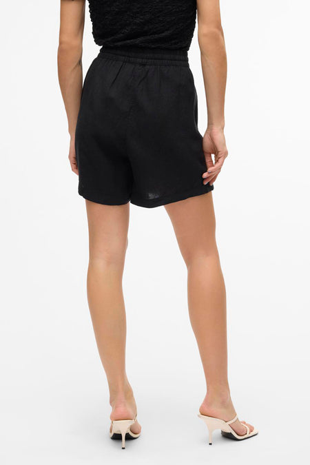 Short noir de VERO MODA, vu de derrière, avec une ceinture élastique et des talons hauts assortis.