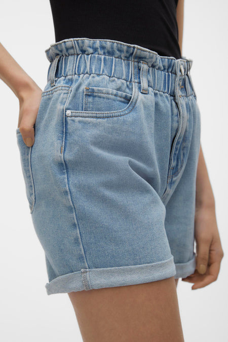 Lichtblauwe denim short van VERO MODA® met een gerimpelde elastische tailleband, voorzakken en opgerolde pijpen, gedragen met een zwarte top.