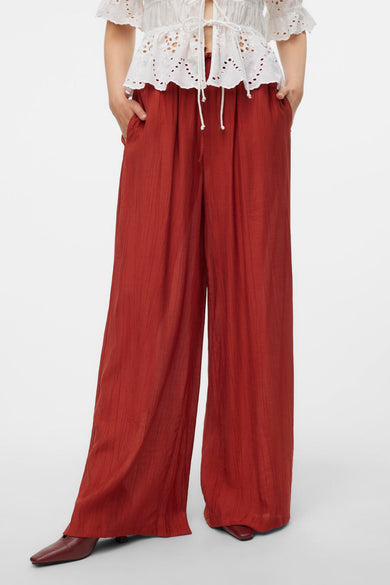 Pantalon marron de Vero Moda avec des lignes verticales, vu de derrière, associé à une blouse blanche.