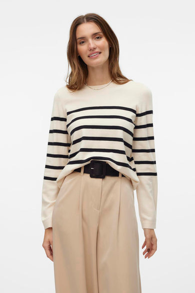 Pull écru à col rond de VERO MODA, avec des rayures noires et des manches longues, sur un modèle avec une jupe beige.