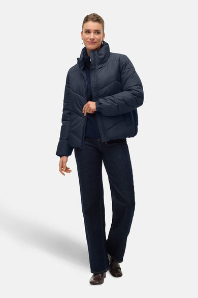 Manteau court bleu de Vero Moda, avec des boutons et porté avec un jeans foncé et des bottines.
