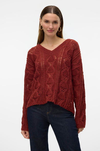 Bruine V-hals trui van VERO MODA® met ajourpatroon en lange mouwen, gedragen met een donkere jeans.
