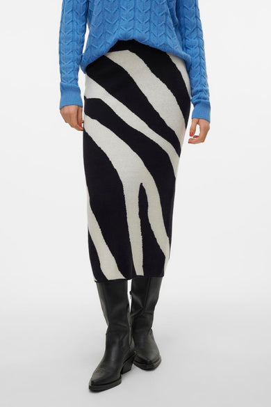 Lange rok met zebraprint van VERO MODA®, gedragen met een blauwe trui en zwarte laarzen, op een witte achtergrond.
