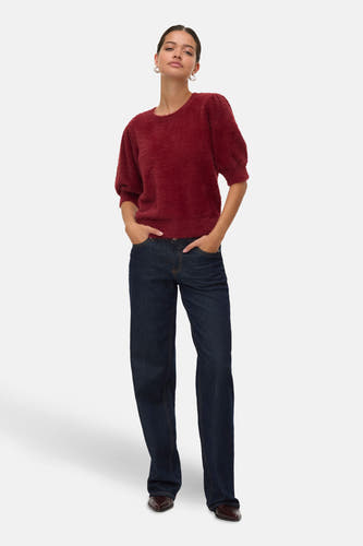 Pull rouge à col rond de VERO MODA, texture douce, associé à des jeans foncés et des chaussures marrons.
