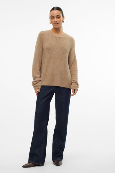 Beige trui met ronde hals van VERO MODA, gedragen met donkerblauwe jeans en bruine schoenen tegen een witte achtergrond.