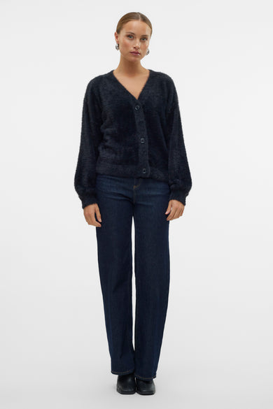 Gilet en velours noir de VERO MODA® avec col en V et boutons, porté avec un jean bleu foncé et des bottes noires, vue de face.