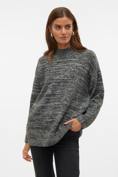 Pull noir à col montant de VERO MODA, avec une texture mélangée, associé à des jeans foncés et des chaussures noires.