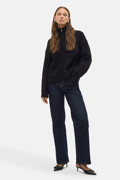 Veste noire de VERO MODA® avec un motif côtelé, une encolure haute et une fermeture à glissière argentée.