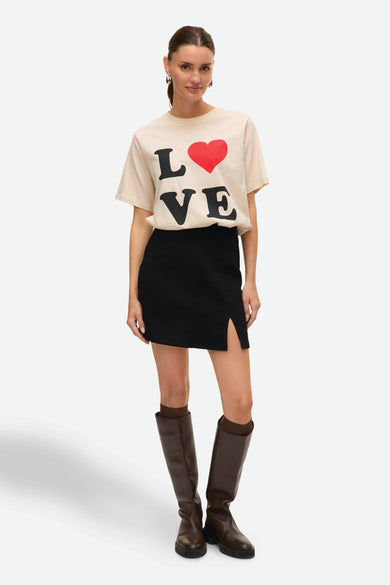 Zwarte korte rok van VERO MODA®, met split aan de voorkant en gecombineerd met bruine kniehoge laarzen.
