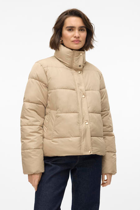 Beige korte jas van Vero Moda met knoopsluiting en hoge kraag, gedragen met donkere jeans.