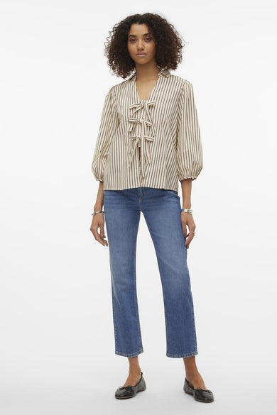 Ecru hemd met korte mouwen van VERO MODA®, gestreept en met strikdetail, gecombineerd met blauwe jeans en zwarte schoenen.
