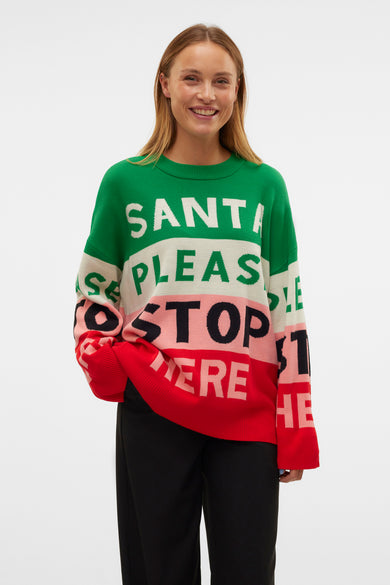 Sweat-shirt multicolore à col rond de VERO MODA, avec le texte "Santa please stop here" et associé à un pantalon noir et des chaussures crème.