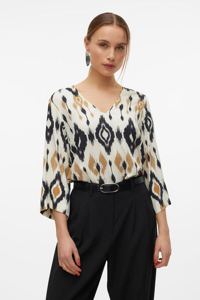 Multikleurige blouse met driekwart mouwen van Vero Moda, met ikatpatroon en gecombineerd met zwarte pantalon en riem.