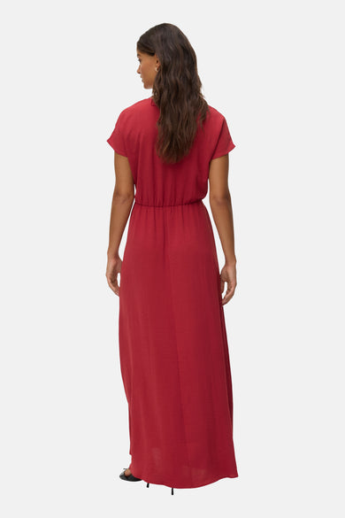 Achterkant van een vrouw met los, bruin haar die een lange, rode jurk draagt.