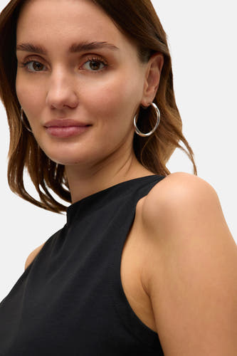 T-shirt noir à manches courtes de VERO MODA, porté avec des boucles d'oreilles en argent dans un plan rapproché.