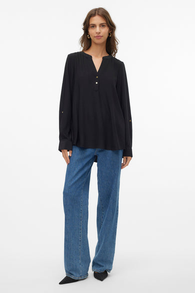 Chemise noire à manches longues de VERO MODA®, avec des boutons dorés et associée à un jean.