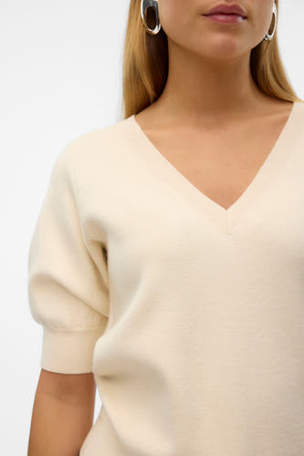 Pull écru avec col V de VERO MODA, avec manches courtes et boucles d'oreilles argentées.
