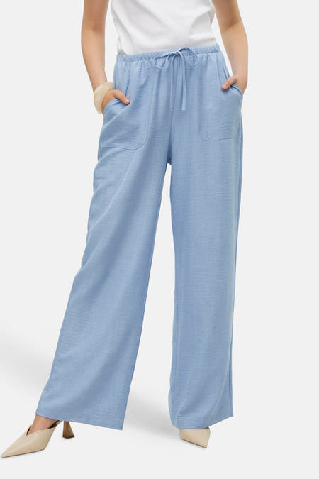 Jean bleu de VERO MODA, associé à un T-shirt blanc, une chaîne en or et des chaussures beige.