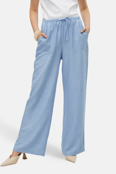 Blauwe colorbroek van VERO MODA, met trekkoord en steekzakken, gecombineerd met beige pumps en een witte top.