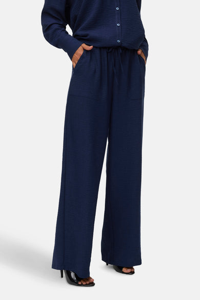 Jean bleu de VERO MODA, avec cordon à la taille et poches fendues, associé à des bottes noires.