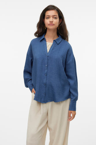 Blauw hemd met lange mouwen van VERO MODA, met knoopsluiting en gedragen met een crèmekleurige top en een crèmekleurige broek.
