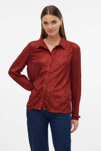 Rood hemd met lange mouwen van VERO MODA, met een kreuktextuur, gedragen met een donkere spijkerbroek.
