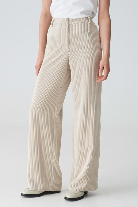 Beige ribfluwelen broek van OPUS met wijde pijpen, gestyled met een wit T-shirt en crèmekleurige instappers.
