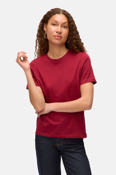 Rood T-shirt met korte mouwen van VERO MODA®, gedragen met donkere jeans en gouden oorbellen.