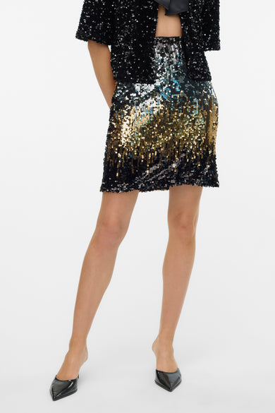 Zwarte korte rok van Vero Moda, versierd met pailletten in goud, zilver en zwart, en gecombineerd met zwarte schoenen.

