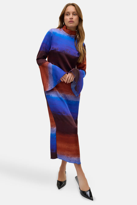 Multikleurige kleedje met lange mouwen van VERO MODA, met een opvallend kleurverloop en uitlopende mouwen, gedragen met zwarte pumps.
