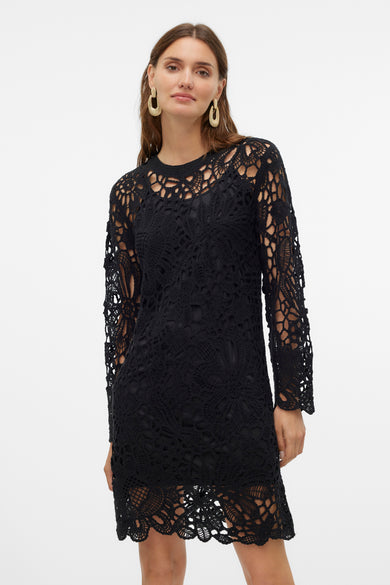 Zwarte jurk met lange mouwen van VERO MODA®, met gehaakt kant en gouden oorbellen.

