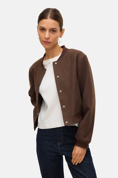 Bruine korte jas van VERO MODA®, met drukknopen, gedragen met een wit shirt en donkerblauwe jeans.
