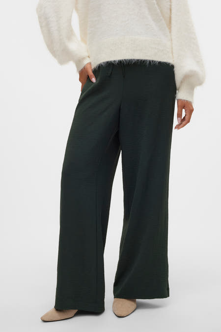 Pantalon vert de VERO MODA, avec texture et larges jambes, associé à une chemise blanche et des chaussures.