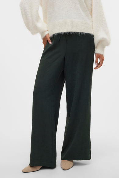 Pantalon vert de VERO MODA, avec texture et larges jambes, associé à une chemise blanche et des chaussures.