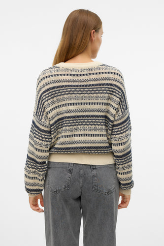 Ecru ronde hals pull van Vero Moda, met blauwe strepen en een geometrisch patroon, gedragen met een grijze jeans.
