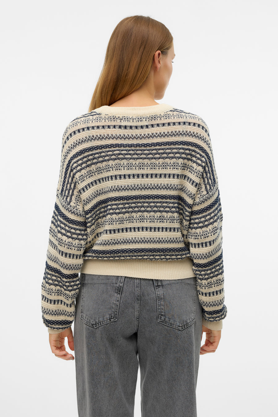 Ecru ronde hals pull van Vero Moda, met blauwe strepen en een geometrisch patroon, gedragen met een grijze jeans.
