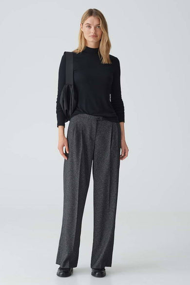 Zwarte trui met ronde hals van OPUS, lange mouwen en gedragen met een grijze pantalon en zwarte tas.
