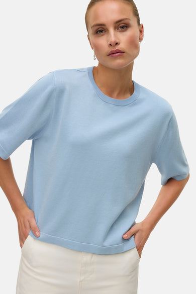 Blauwe trui met ronde hals van VERO MODA, effen design, gedragen met een witte broek en zilverkleurige oorbellen.