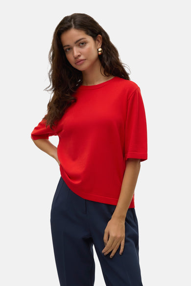 Rode trui met ronde hals van VERO MODA®, met korte mouwen en een gladde textuur, gecombineerd met marineblauwe pantalon.
